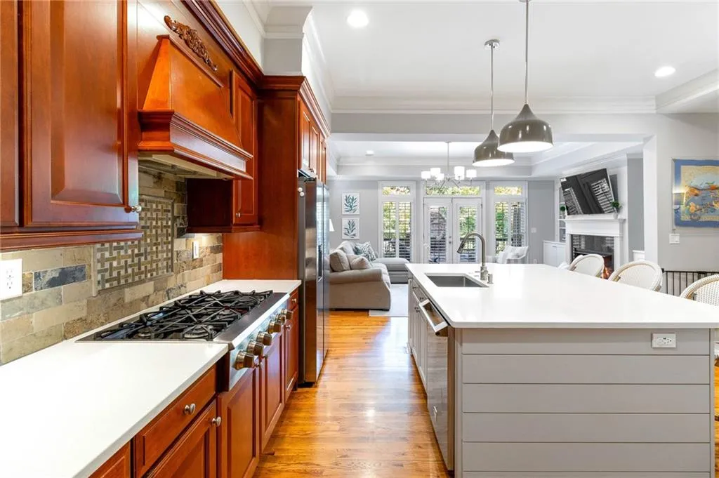 Kitchen featuring a kitchen island with sink, decorative light fixtures, a kitchen breakfast bar, premium range hood, and sink