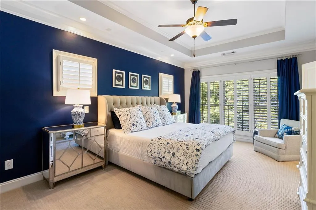 Carpeted bedroom featuring crown molding, ceiling fan, and a raised ceiling
