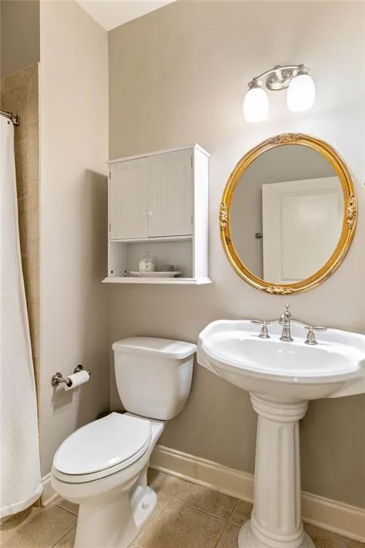 Bathroom with a shower with shower curtain, tile patterned flooring, toilet, and sink