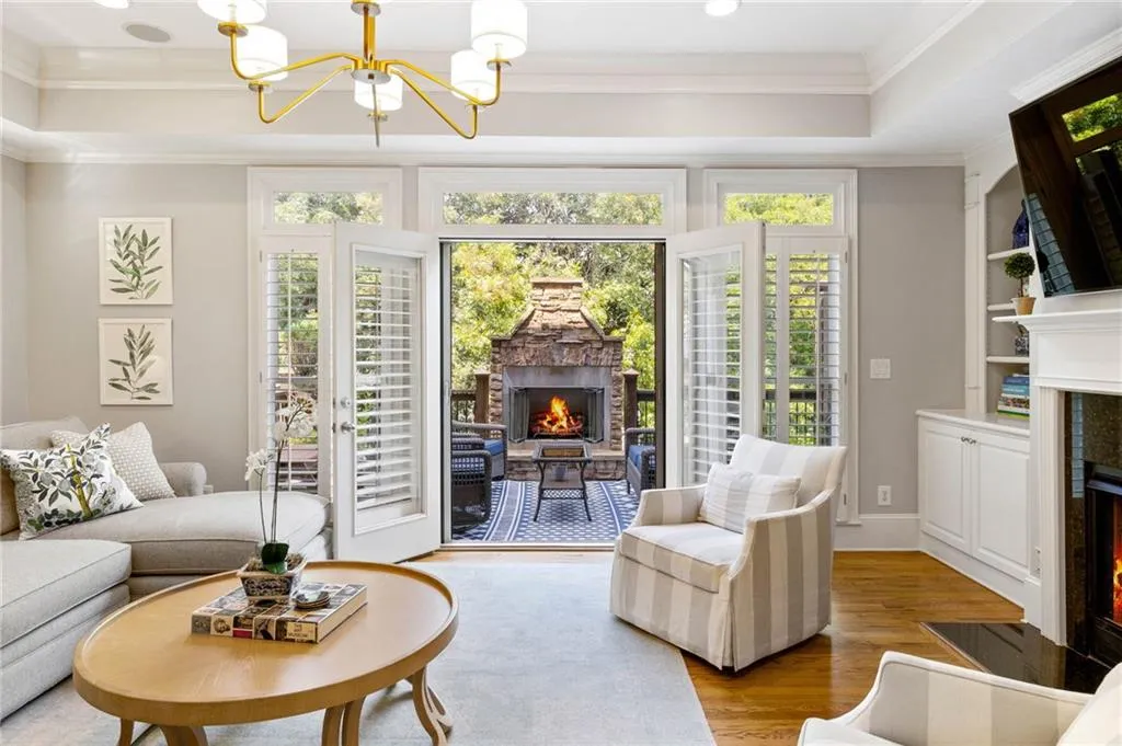 Living room with light wood-type flooring, built in shelves, a chandelier, and ornamental molding