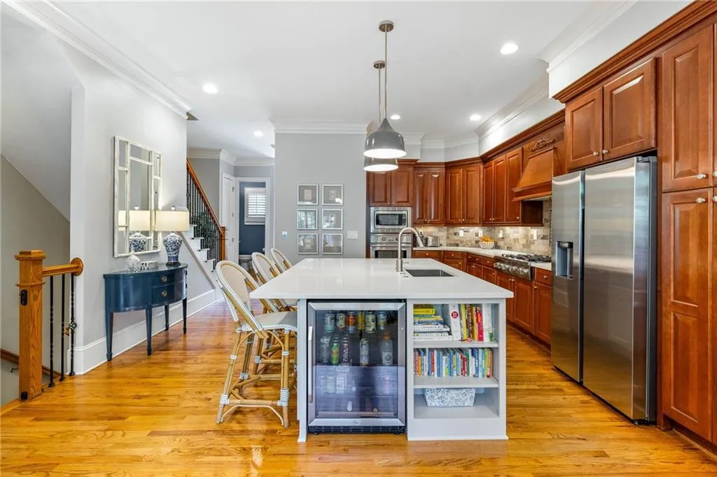 Kitchen with a kitchen breakfast bar, a center island with sink, light hardwood / wood-style flooring, beverage cooler, and stainless steel appliances