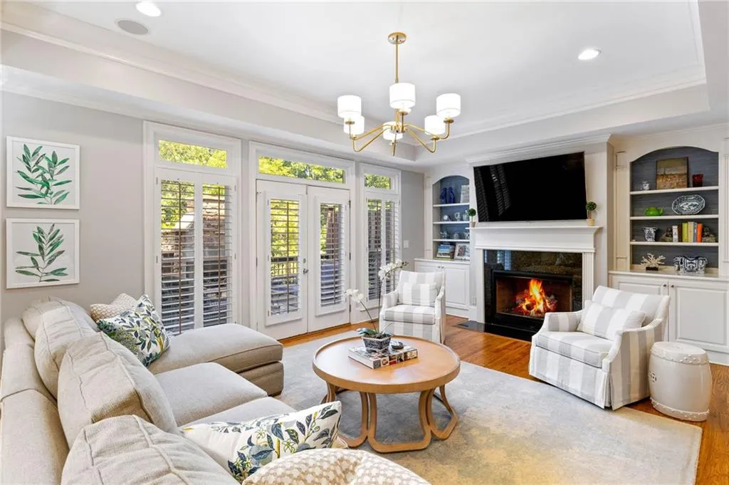 Living room featuring a fireplace, built in features, ornamental molding, hardwood / wood-style flooring, and a chandelier