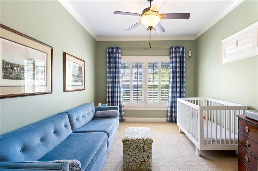 Bedroom with crown molding, a nursery area, ceiling fan, and light carpet