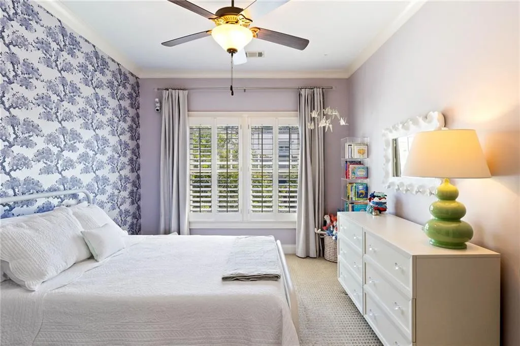 Bedroom with light carpet, ornamental molding, and ceiling fan