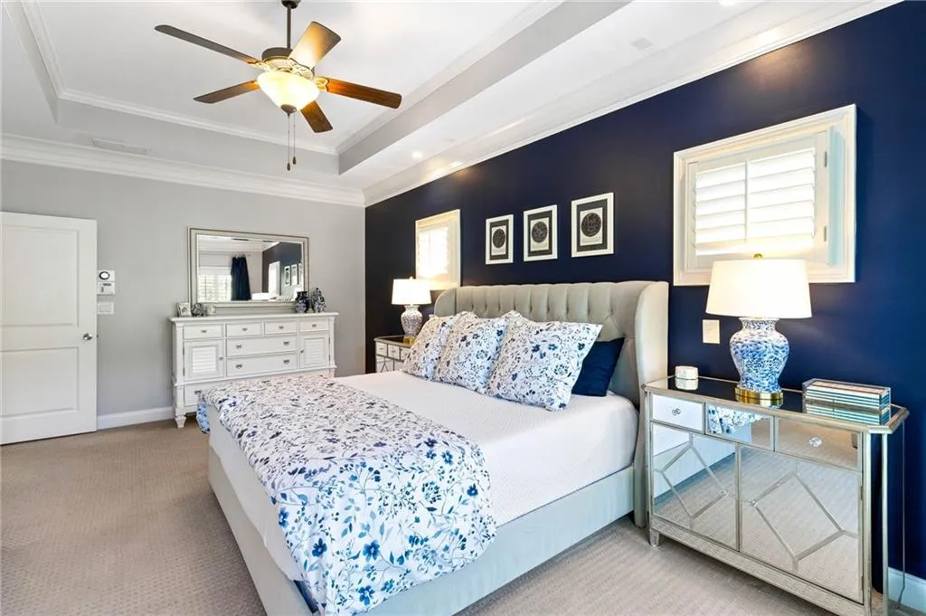 Bedroom with light carpet, ceiling fan, a raised ceiling, and crown molding