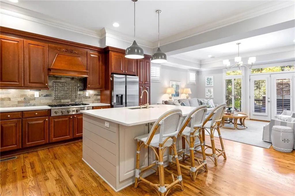 Kitchen featuring decorative light fixtures, premium range hood, stainless steel appliances, and a center island with sink