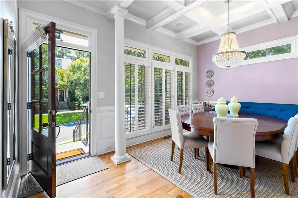 Dining room featuring light wood-type flooring, coffered ceiling, a wealth of natural light, and ornate columns