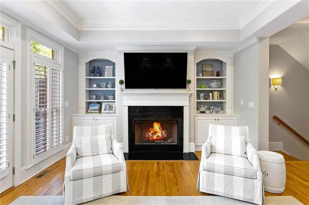 Living room with crown molding, light hardwood / wood-style flooring, a tray ceiling, and a fireplace