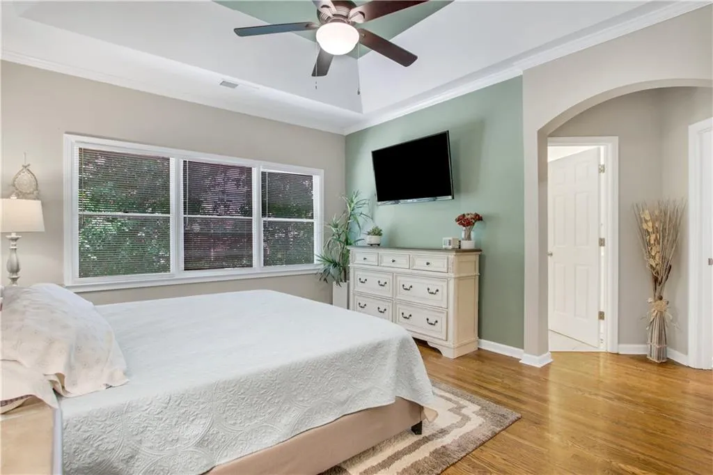 Bedroom with ceiling fan, light wood-type flooring, and crown molding