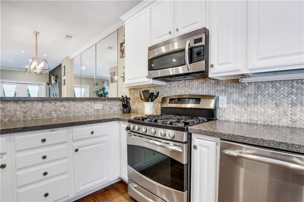 Kitchen with decorative backsplash, appliances with stainless steel finishes, and dark wood-type flooring