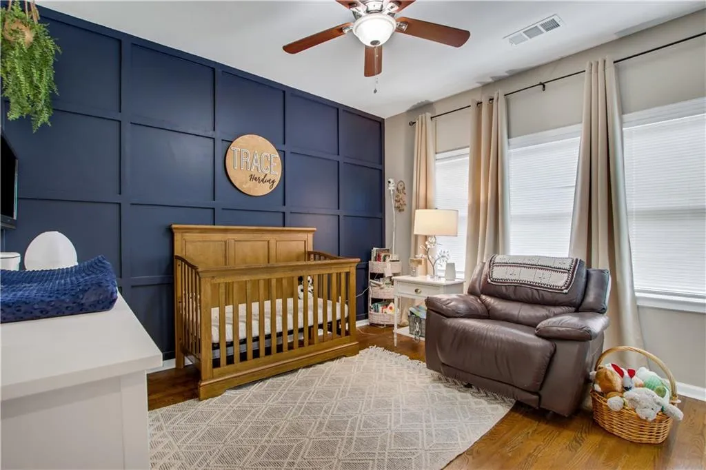 Bedroom featuring wood-type flooring, a crib, and ceiling fan