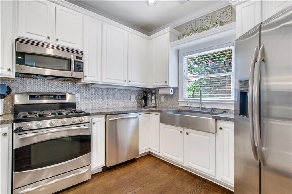 Kitchen with white cabinetry, tasteful backsplash, stainless steel appliances, dark hardwood / wood-style flooring, and sink