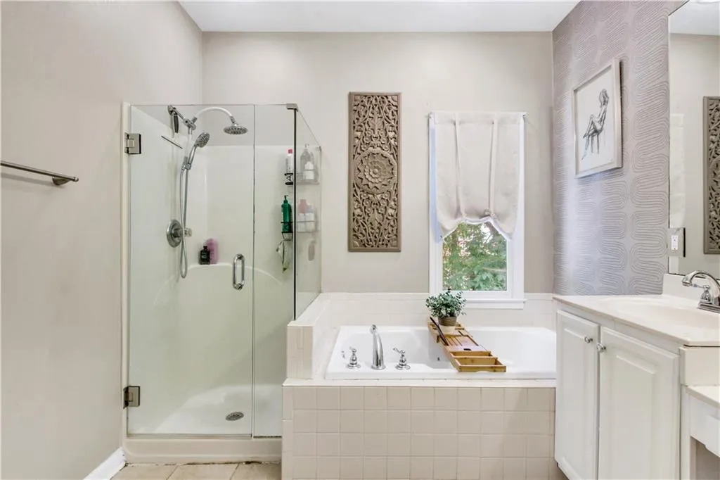 Bathroom featuring tile patterned flooring, shower with separate bathtub, and vanity