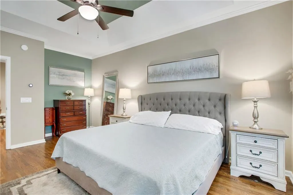 Bedroom featuring hardwood / wood-style flooring, crown molding, and ceiling fan