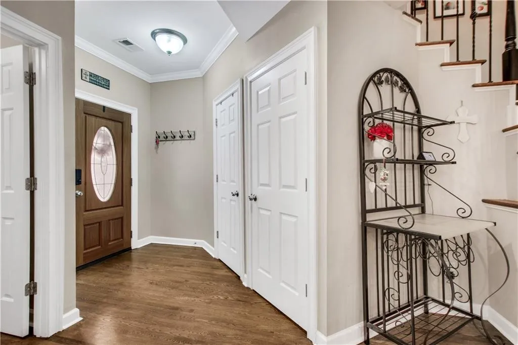 Entrance foyer with dark hardwood / wood-style floors and crown molding