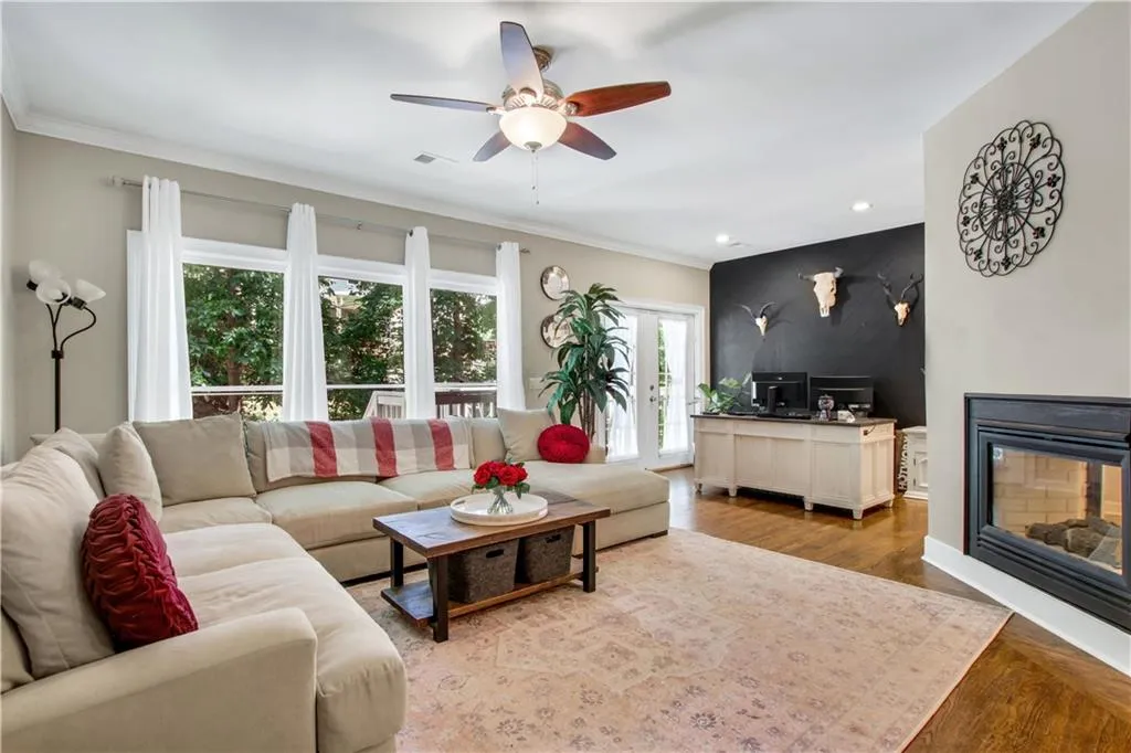 Living room with crown molding, light hardwood / wood-style flooring, a multi sided fireplace, and ceiling fan