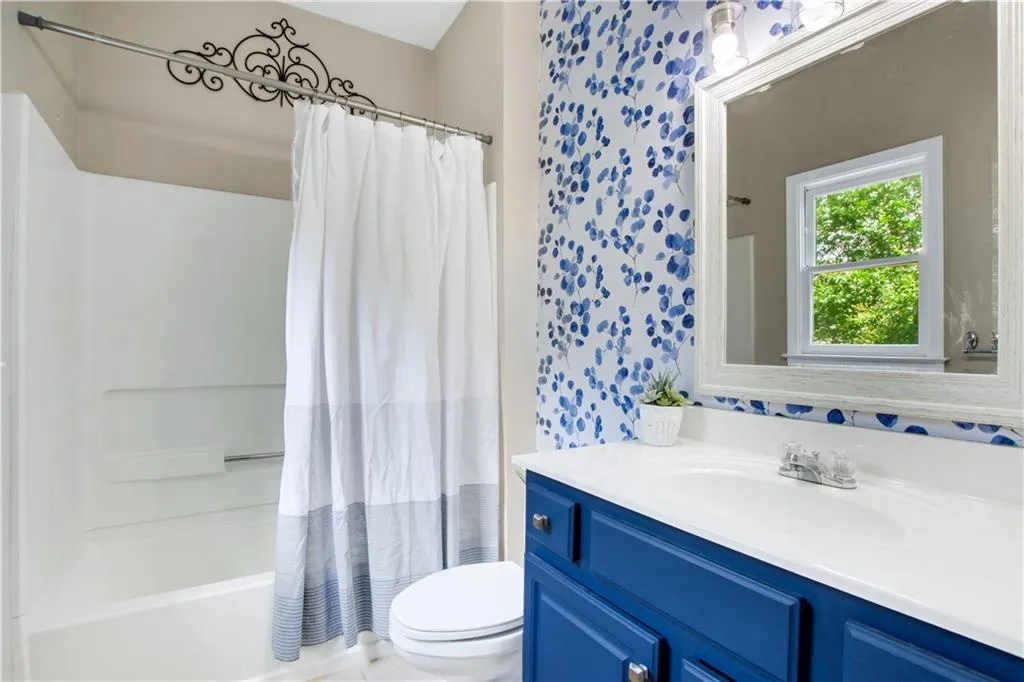 Full bathroom featuring shower / tub combo with curtain, vanity, and toilet