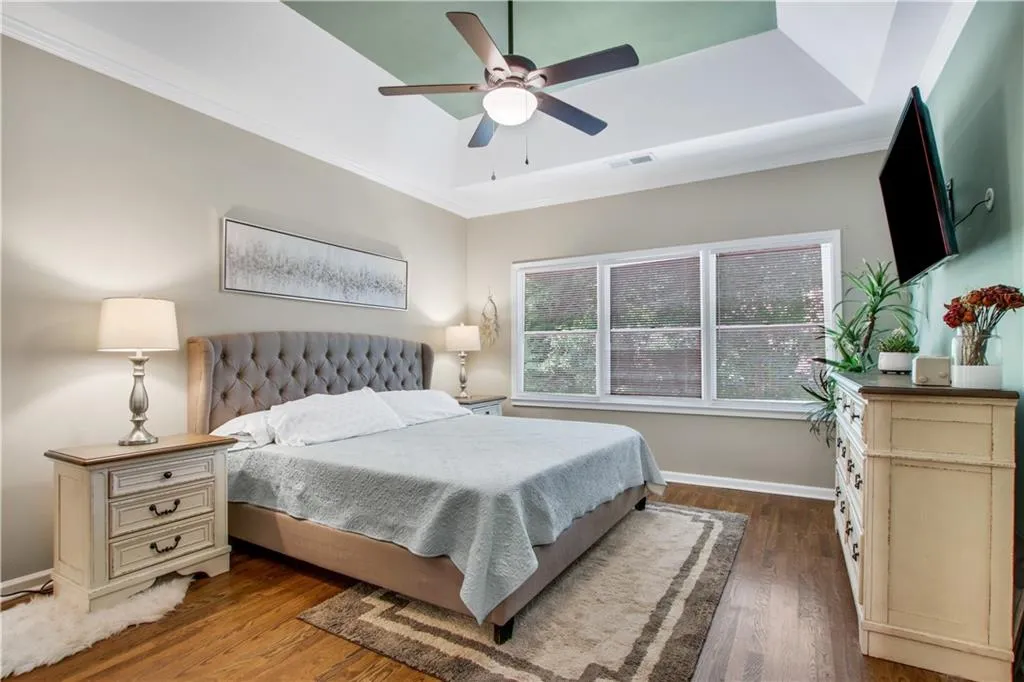 Bedroom with ceiling fan, a tray ceiling, hardwood / wood-style flooring, and ornamental molding