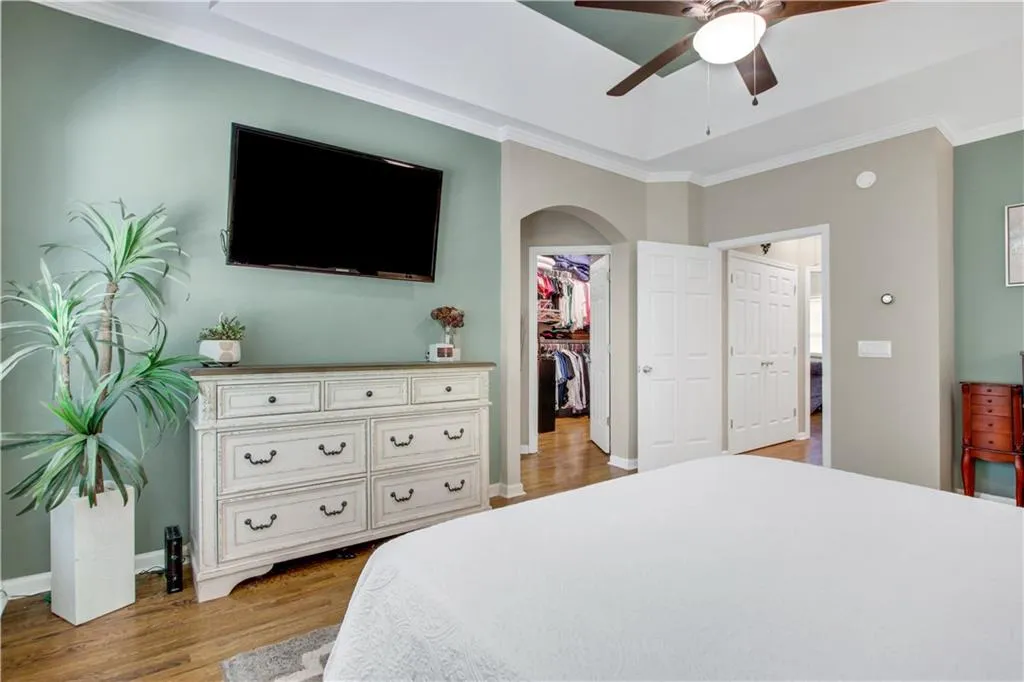 Bedroom featuring light hardwood / wood-style flooring, ceiling fan, a walk in closet, a closet, and ornamental molding