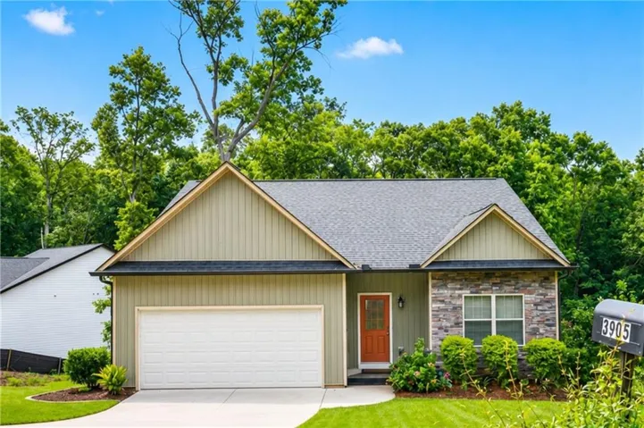 Craftsman-style exterior featuring a prominent gable roofline, light green vertical siding, and a stone facade accent