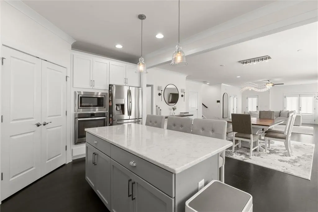 Kitchen featuring a central island with countertop seating, stainless steel appliances, white cabinetry, and dark wood-finish flooring
