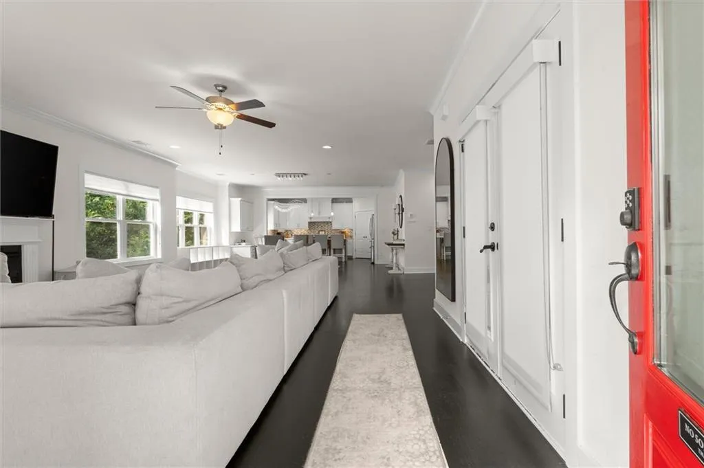 Bright open-concept living area with dark wood-finish flooring, recessed lighting, and a ceiling fan