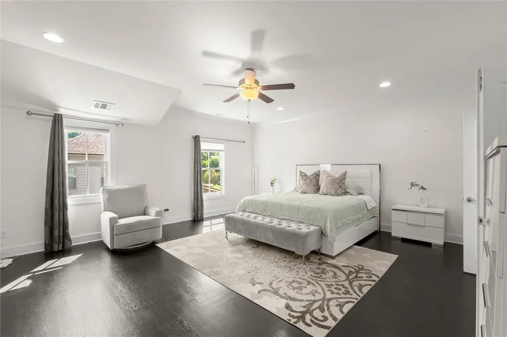 Dark wood-finish flooring with white baseboards, recessed lighting, and a ceiling fan