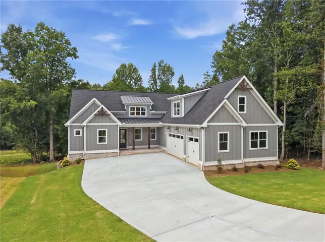 Craftsman-style exterior with gray siding and white trim, featuring a dark shingle roof and a covered porch with wood-finish columns