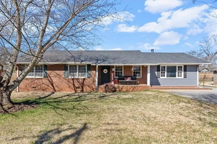 Single-story residence featuring brick and siding facade, a dark shingle roof, white window trim with dark shutters, and a covered front porch