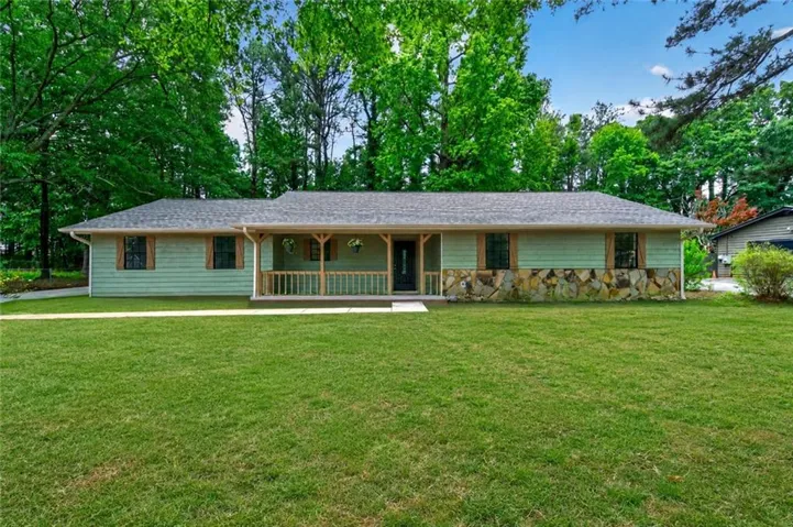 Ranch-style exterior featuring light green siding, a stone veneer foundation, and a gray shingle roof