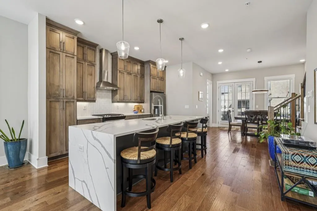 Chef's Kitchen impresses with a Massive Quartz Waterfall Island, Beautiful Stained Cabinetry, Stainless Steel Appliances, and a Timeless White Subway Tile Backsplash.