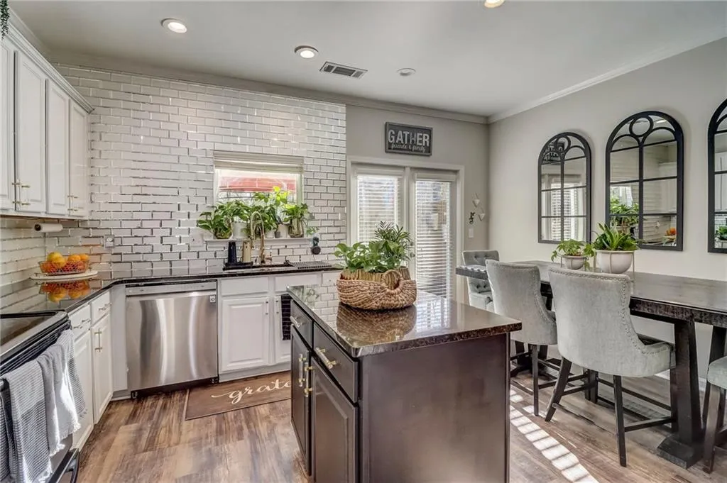 Kitchen featuring ornamental molding, dark stone counters, dishwasher, tasteful backsplash, and a center island