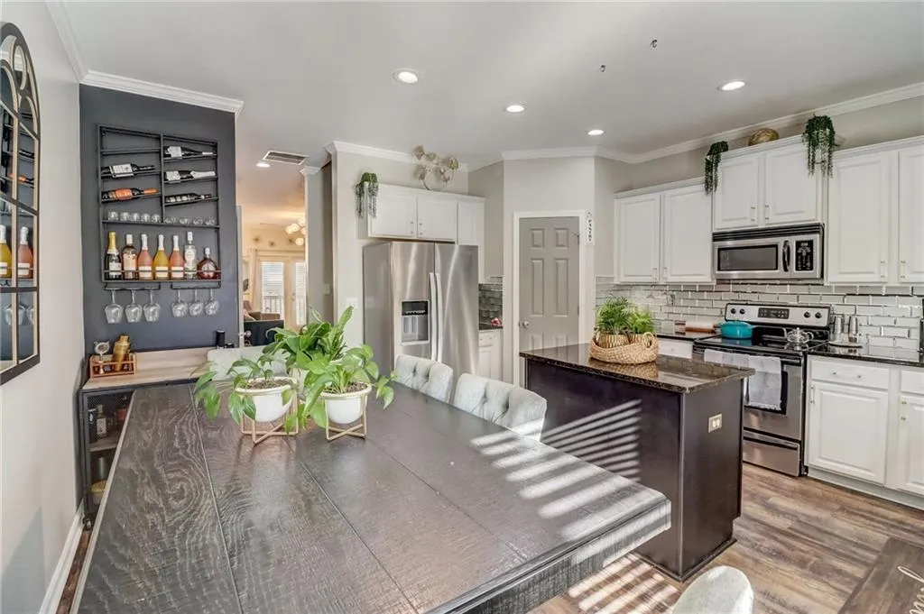 Kitchen with white cabinetry, stainless steel appliances, dark stone counters, ornamental molding, and recessed lighting