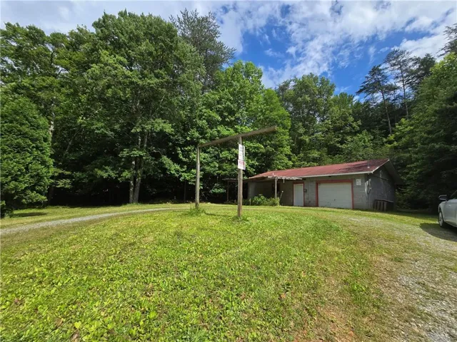 View of grassy yard featuring an outbuilding and a detached garage