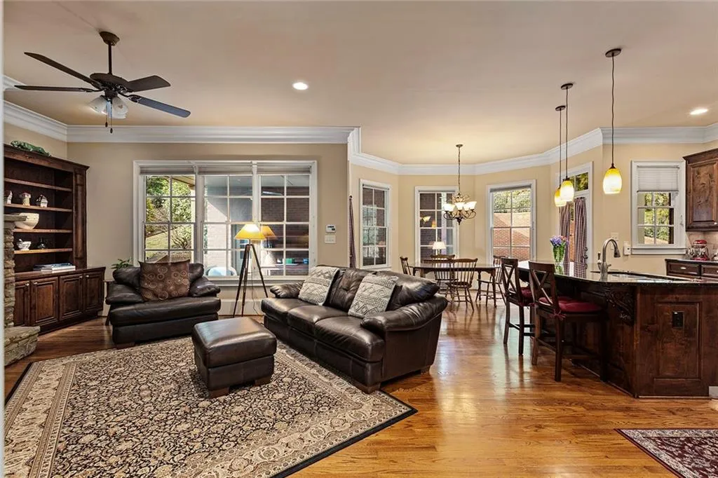 Living room featuring sink, ceiling fan with notable chandelier, ornamental molding, and light hardwood / wood-style floors