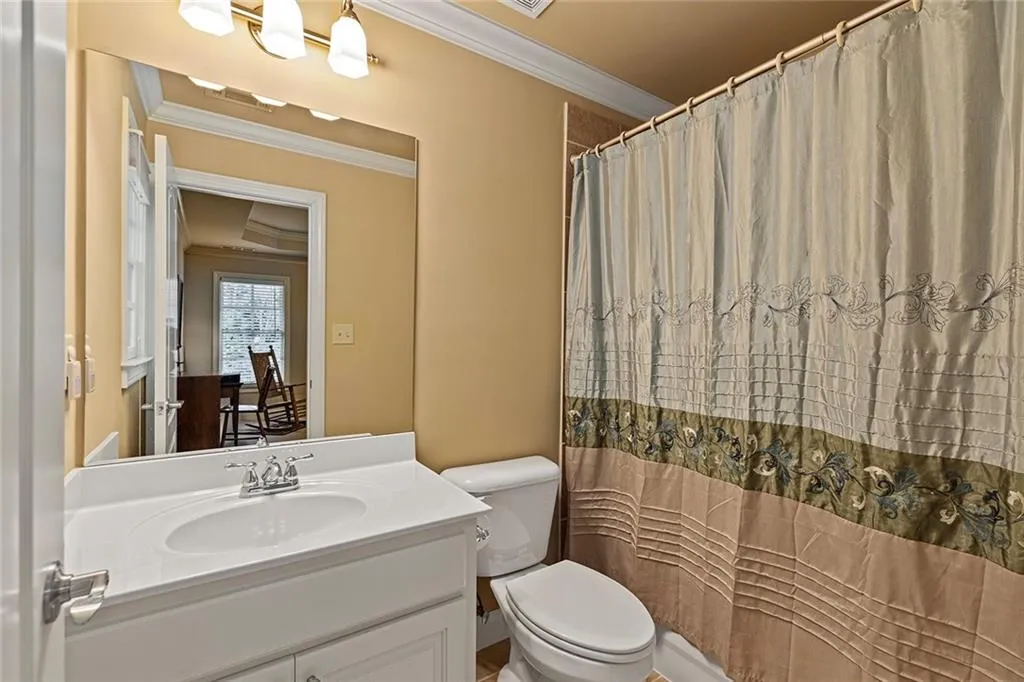 En suite bathroom featuring vanity, crown molding, and toilet