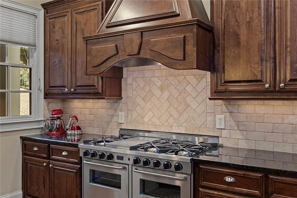 Kitchen featuring range with two ovens, dark brown cabinets, and backsplash