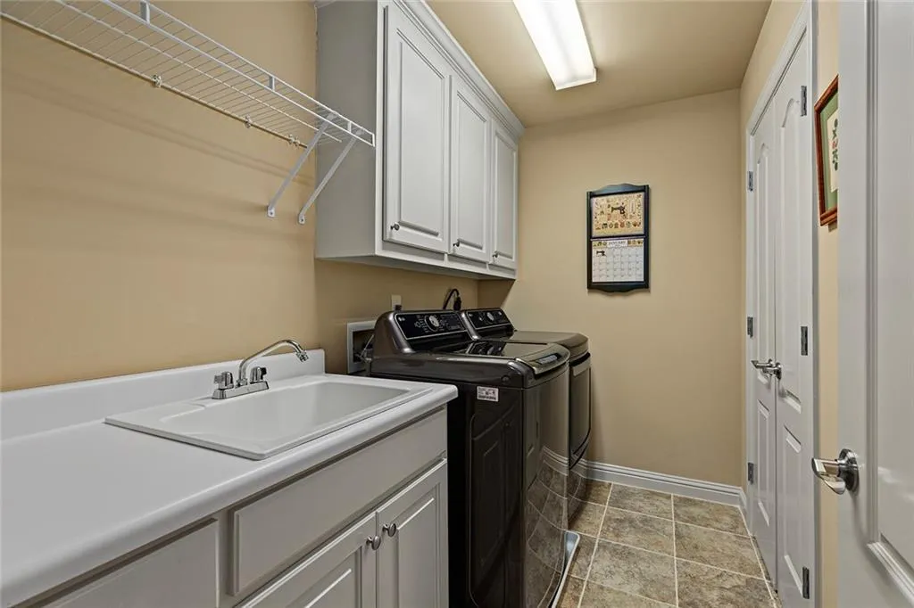 Laundry area featuring separate washer and dryer, sink, and cabinets