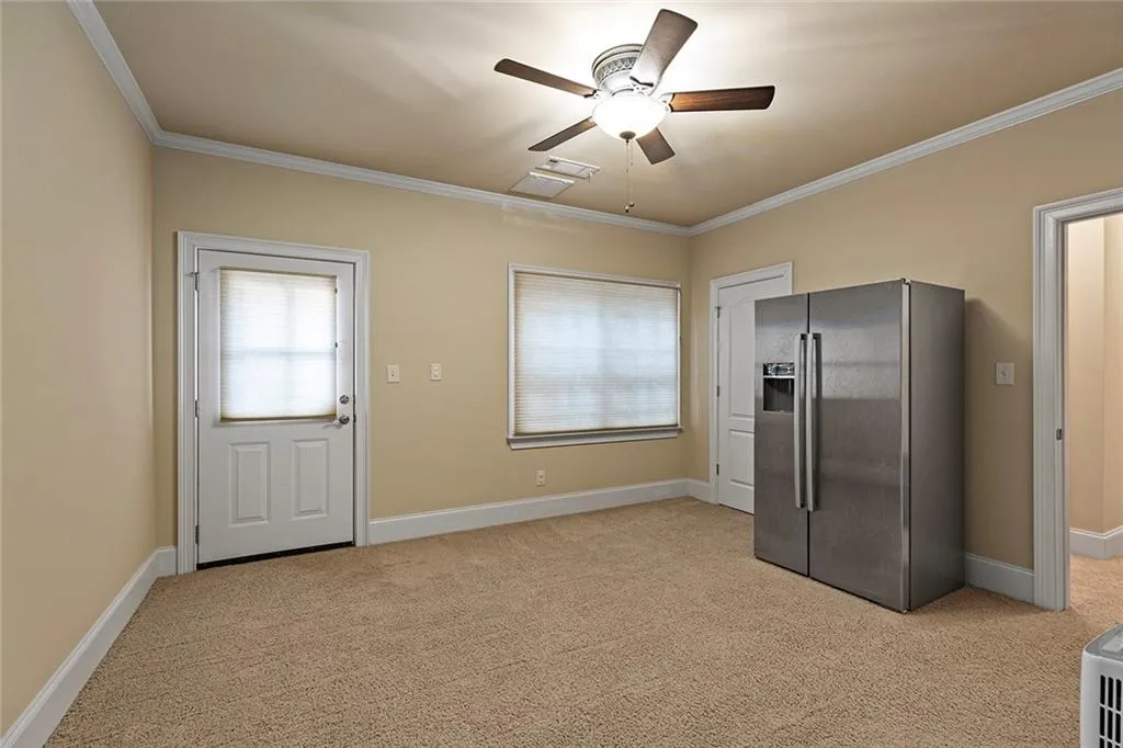 Basement level Bedroom with crown molding, light colored carpet, and stainless steel fridge