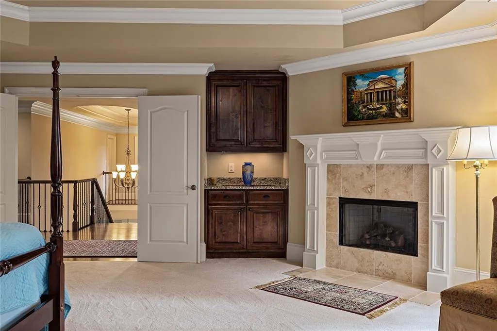 Living room featuring a tiled fireplace, crown molding, light colored carpet, and a chandelier