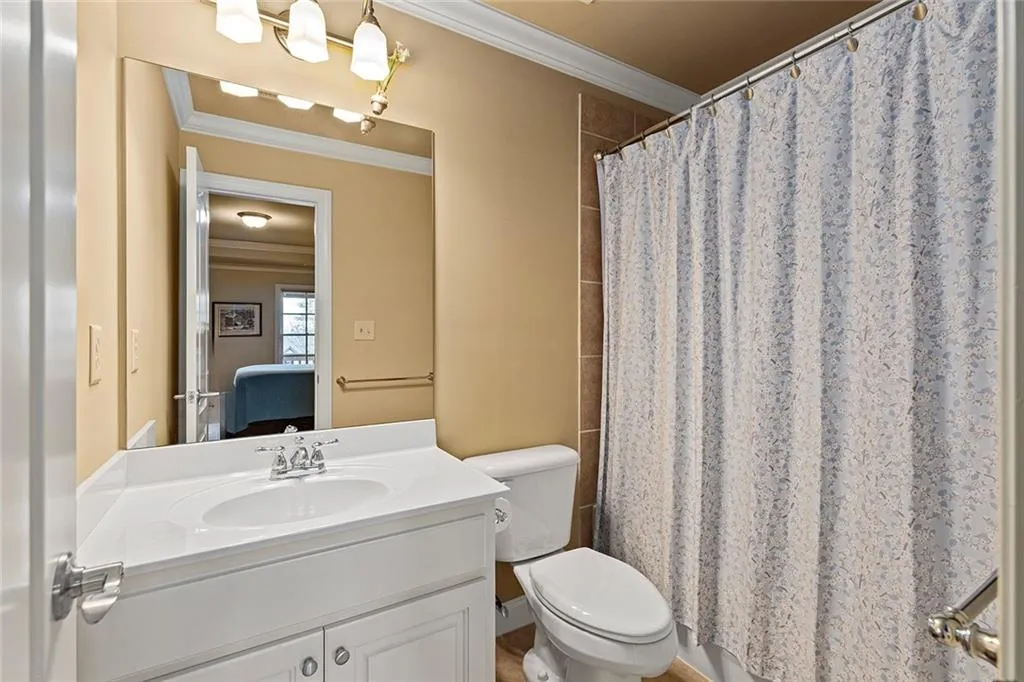 En suite bathroom with vanity, ornamental molding, toilet, and a shower with shower curtain