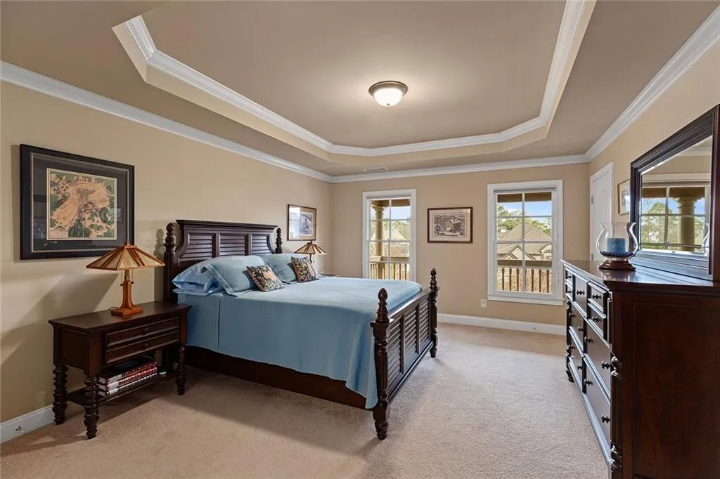 Bedroom with crown molding, light colored carpet, and a tray ceiling