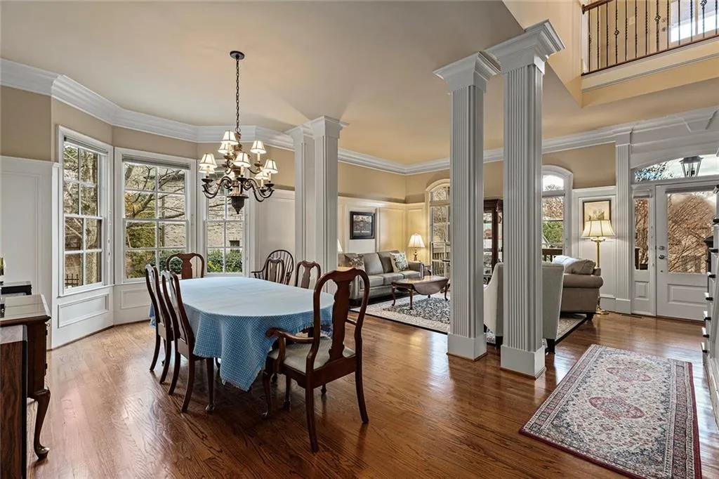 Dining space with hardwood / wood-style flooring, crown molding, decorative columns, and a notable chandelier