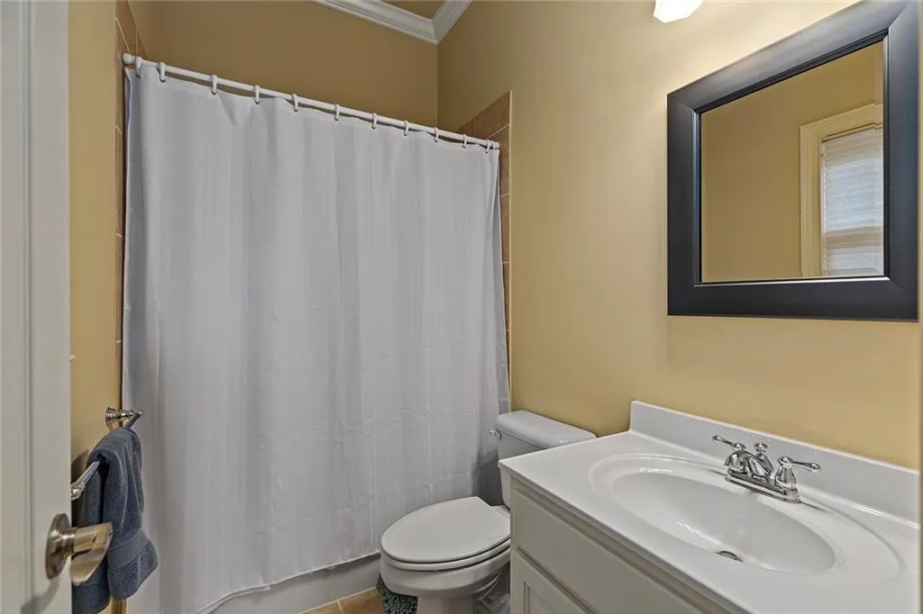 Bathroom with crown molding, curtained shower, vanity, and toilet
