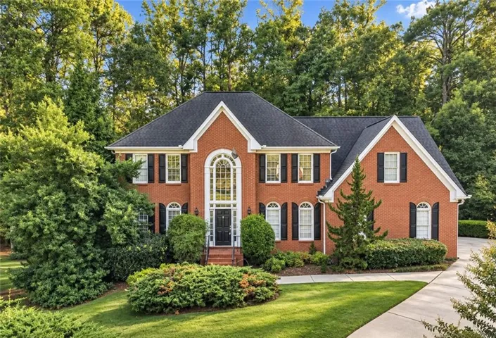 Brick exterior with dark shutters, prominent arched window, dark entry door, and gabled roofline