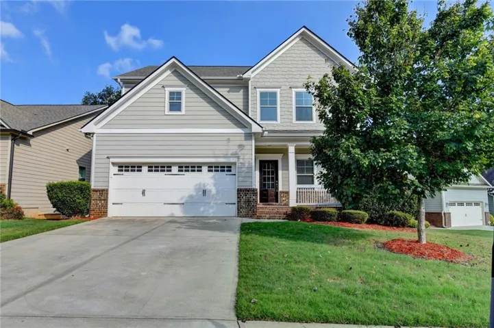 Two-story residence featuring light gray siding, a covered front porch, and an attached two-car garage