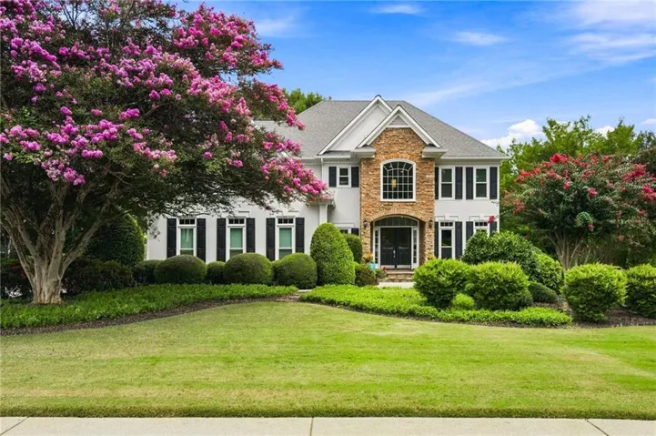 Traditional-style residence featuring a stone and siding exterior, arched transom window, and a prominent front entrance