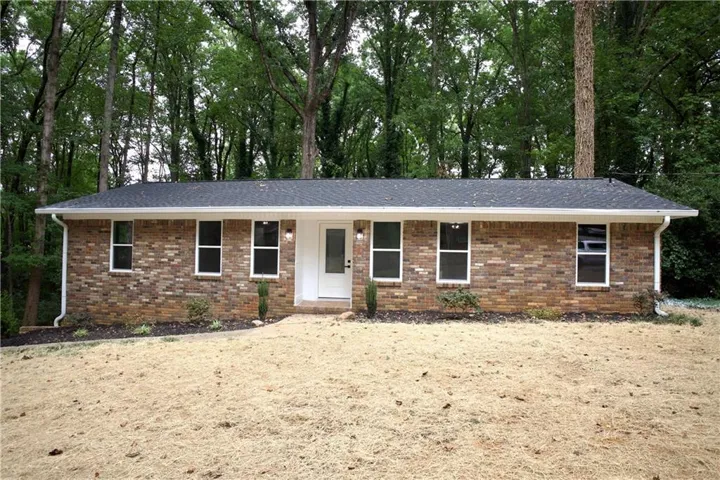 Brick exterior with a dark shingle roof, white trim, and a prominent white front door