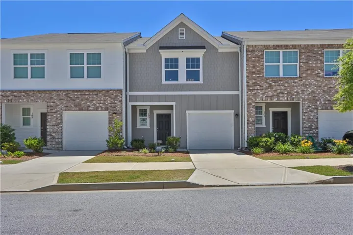 Three-unit townhouse complex featuring varied exterior finishes including brick veneer, horizontal siding, and shake siding