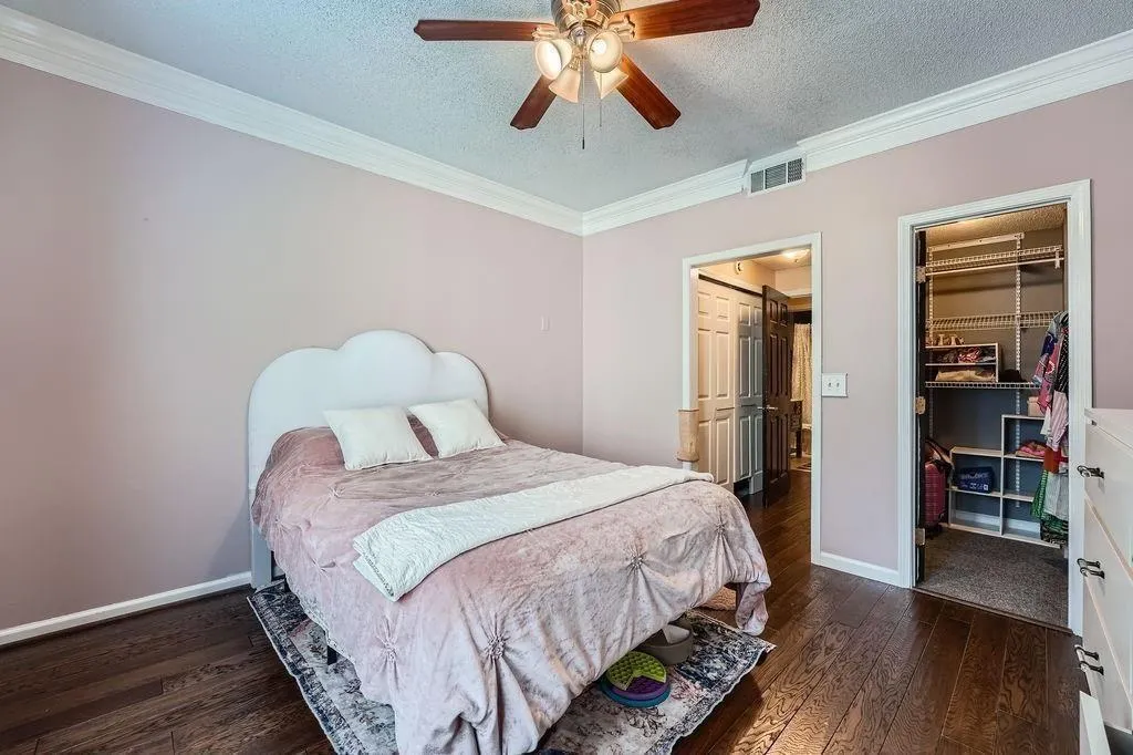 Bedroom featuring a walk in closet, hardwood / wood-style floors, a textured ceiling, crown molding, and a closet